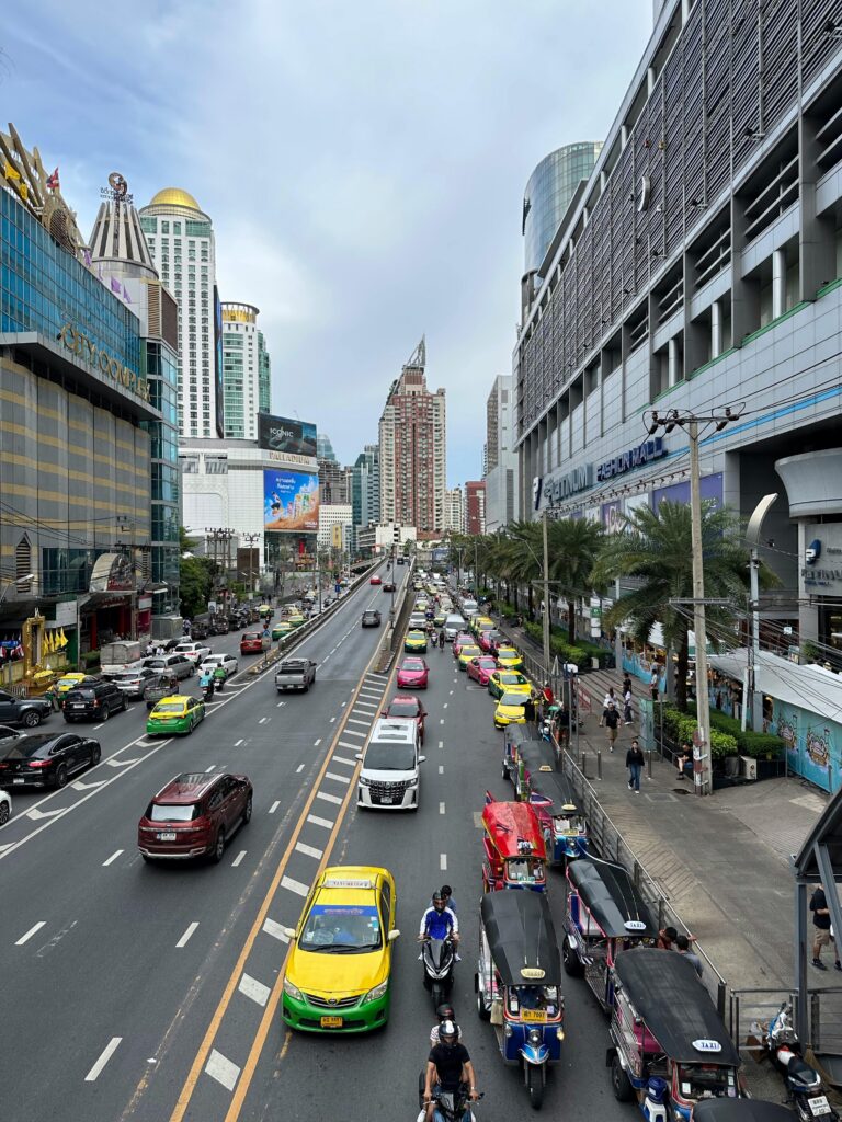 Vibrant Bangkok street scene featuring Tuk-Tuks and high-rise buildings.
