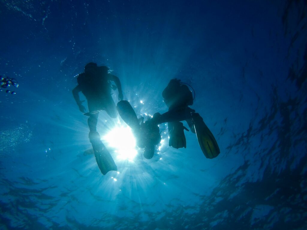 Silhouette of scuba divers with sun rays underwater in Koh Tao, Thailand.
